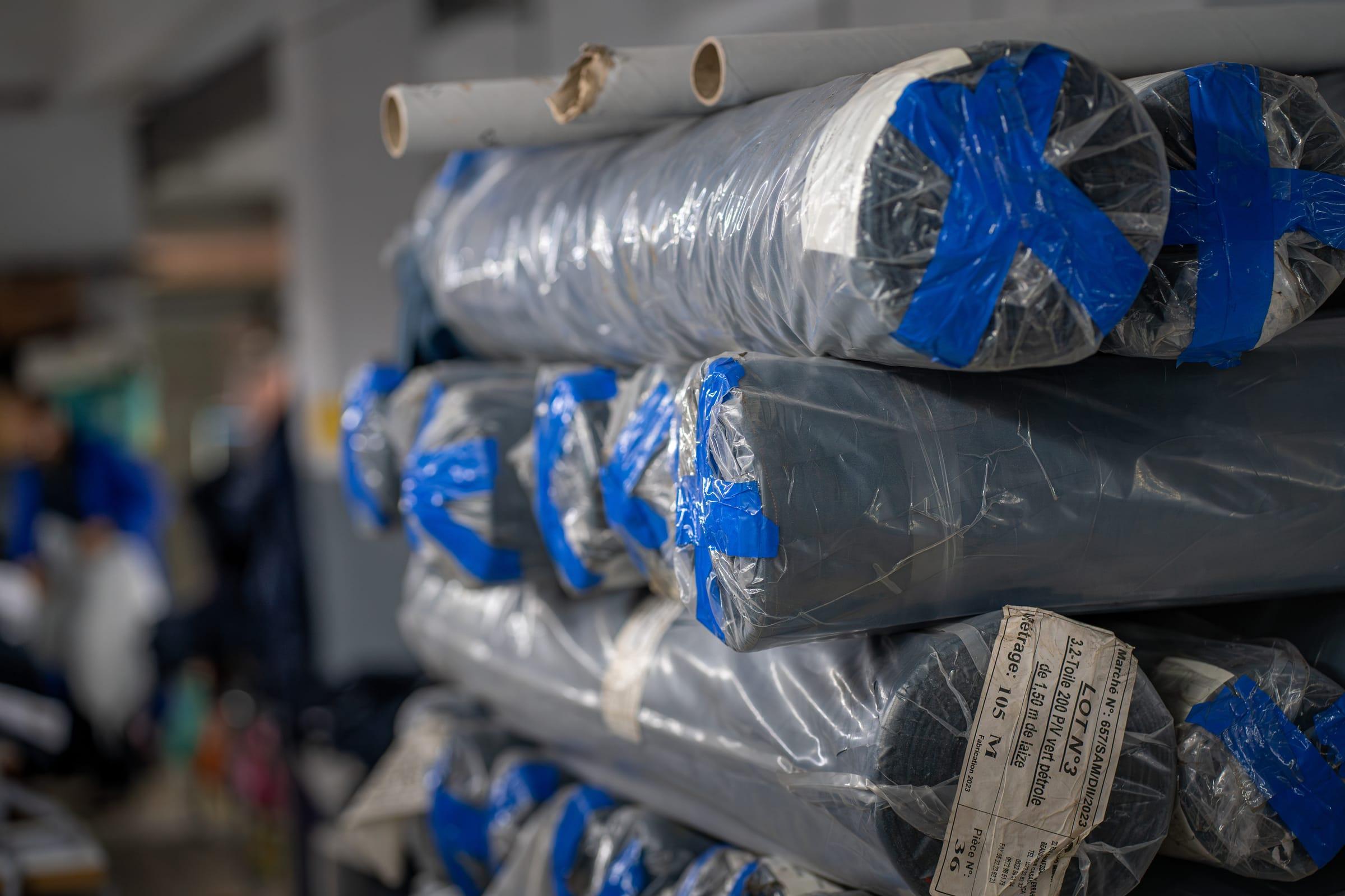 Rouleaux de tissu emballés et étiquetés, stockés dans l'atelier avant la coupe